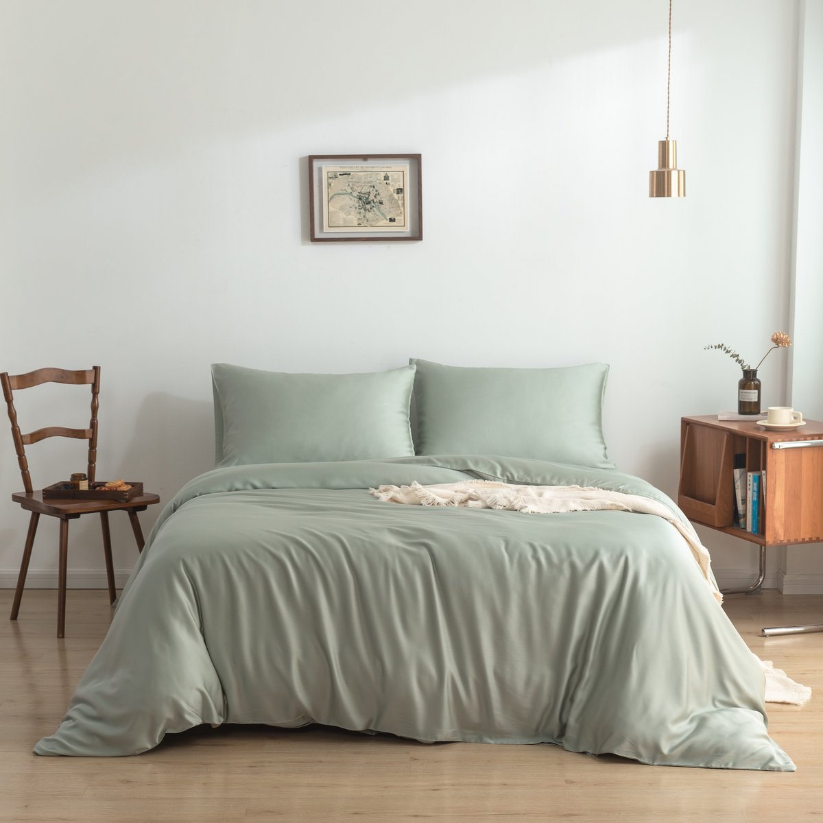 Bamboo duvet cover in Sage Green on a bed beside a wooden chair in a minimalist bedroom