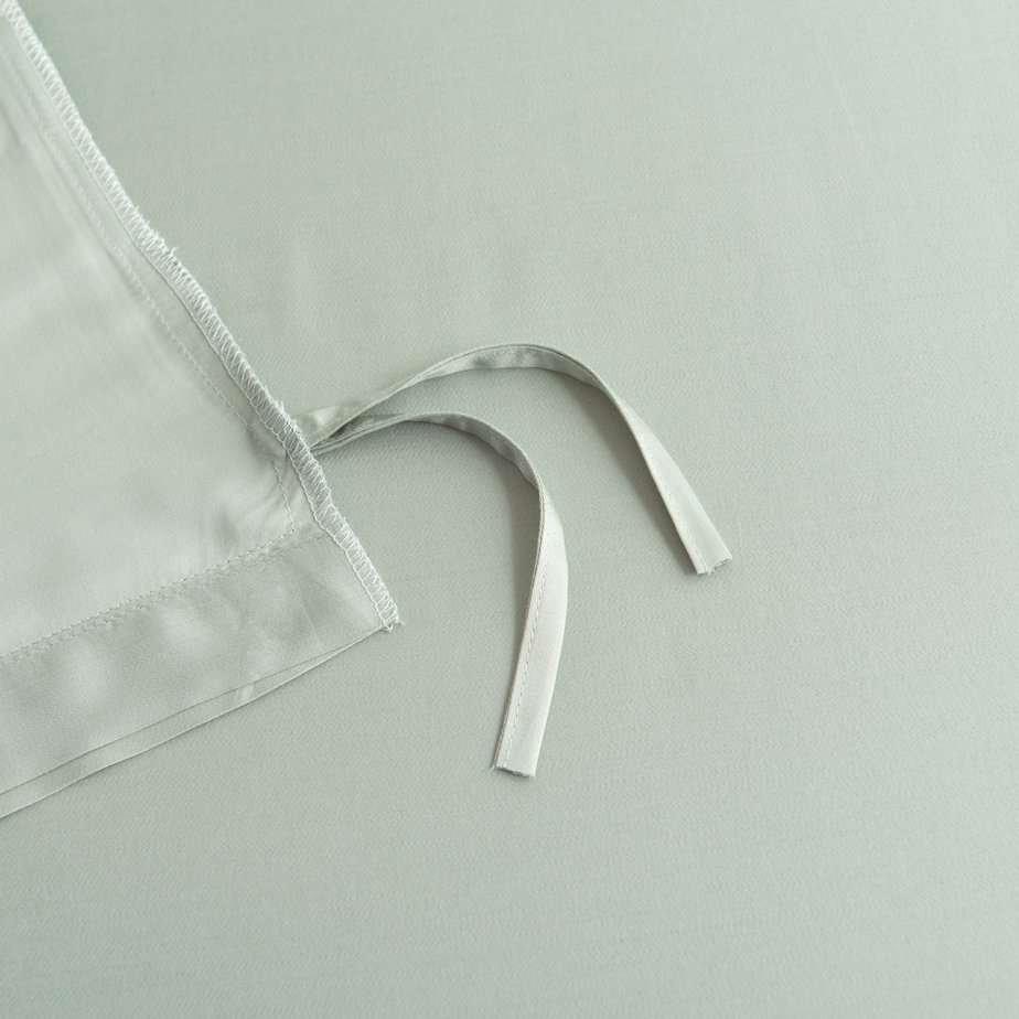 Close-up of the tuck-in strip ties on the corner of the Sage Green bamboo duvet cover