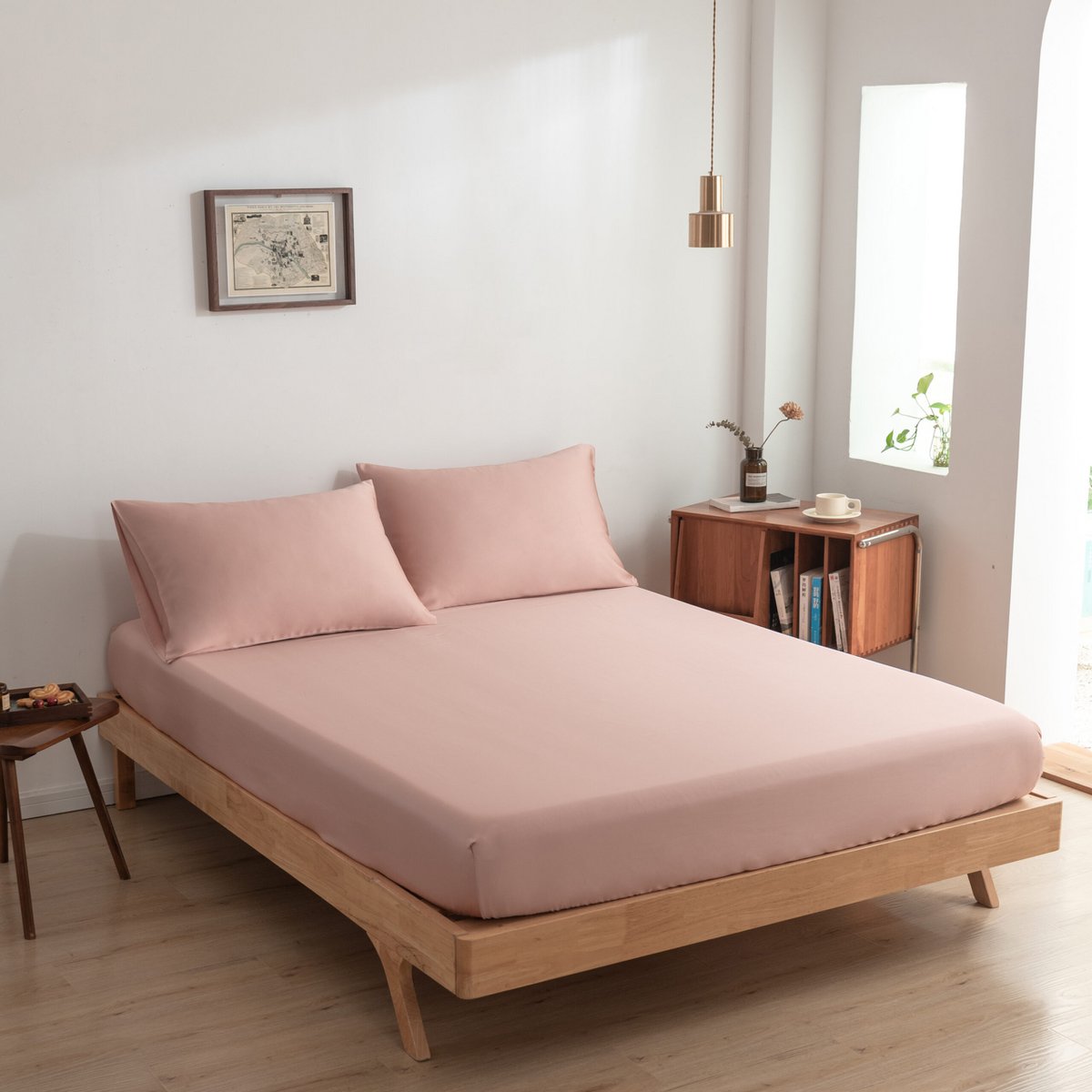 Cuddle Pink bamboo fitted sheet on a wood-frame bed in a full bedroom view with a window.