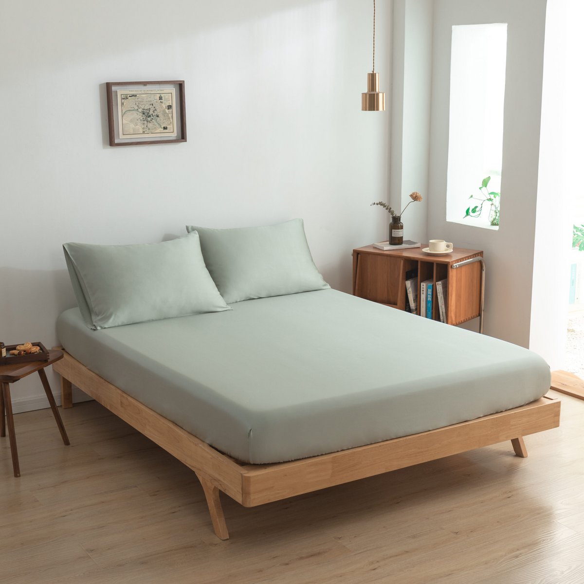 Sage Green bamboo fitted sheet styled on a wood-frame bed in a bright bedroom.