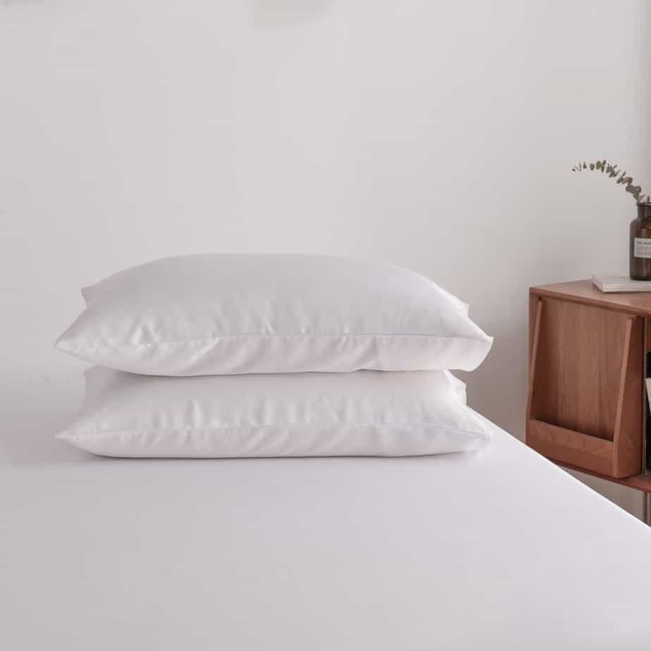 Coco White bamboo pillowcases styled on a bench in a bedroom setting