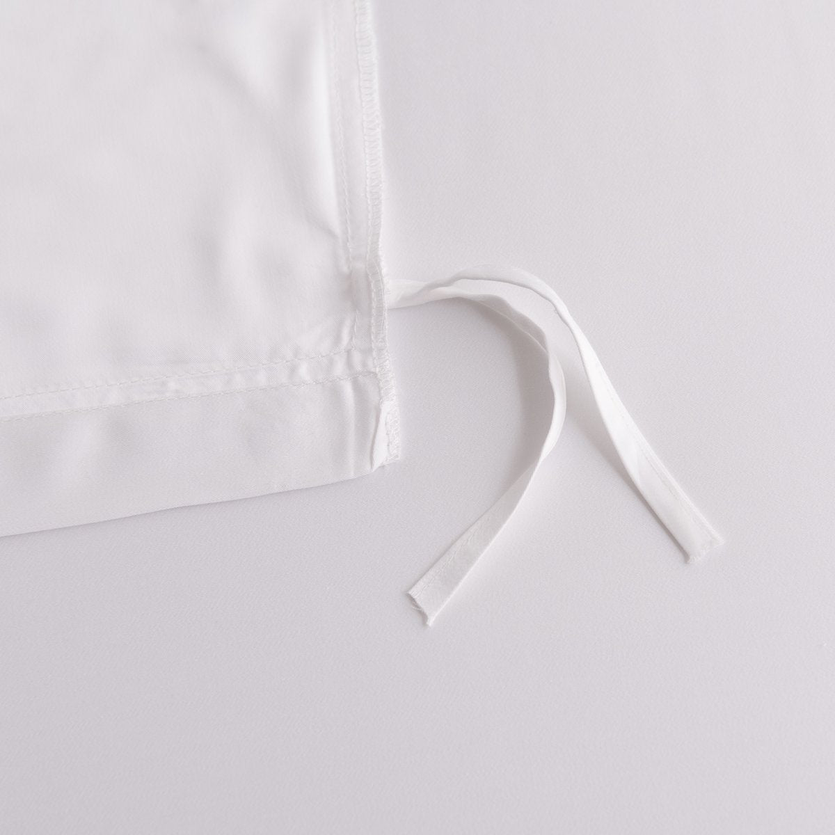 Close-up of the white fabric tuck-in strip ties on the corner of the Coco White bamboo duvet cover