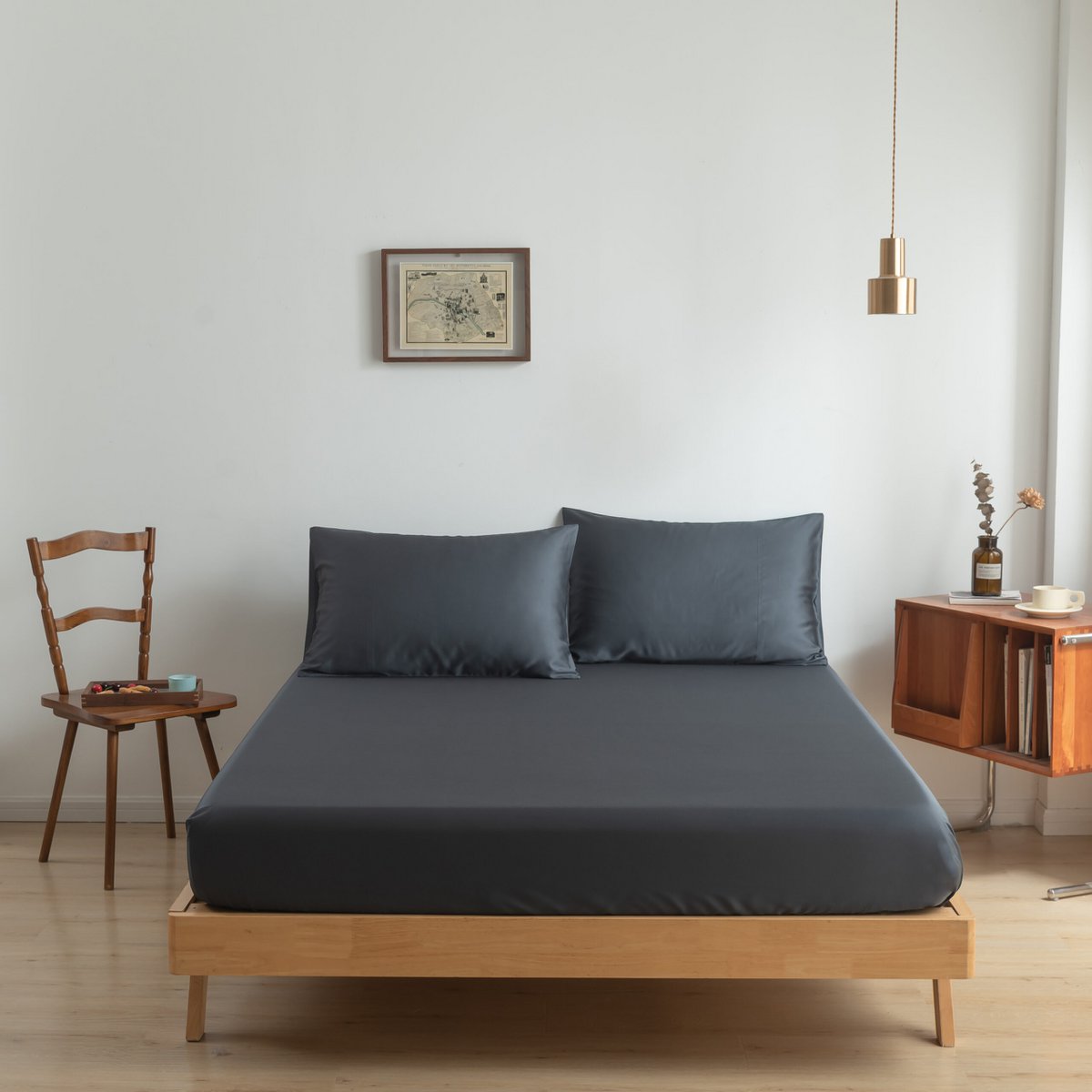 Space Blue bamboo fitted sheet on a made bed, shown straight-on with two matching pillows.