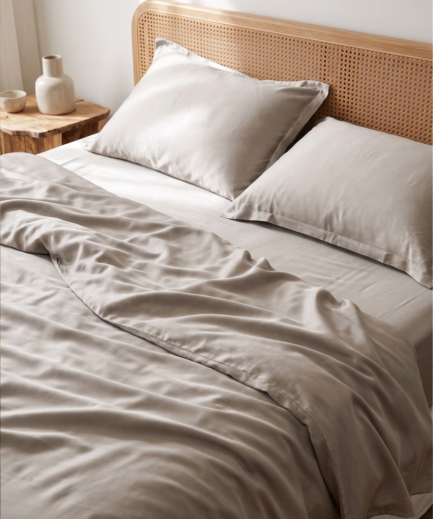 Seidig-taupefarbene TENCEL & Lyocell Bettwäsche auf einem Bett mit Rattan-Kopfteil