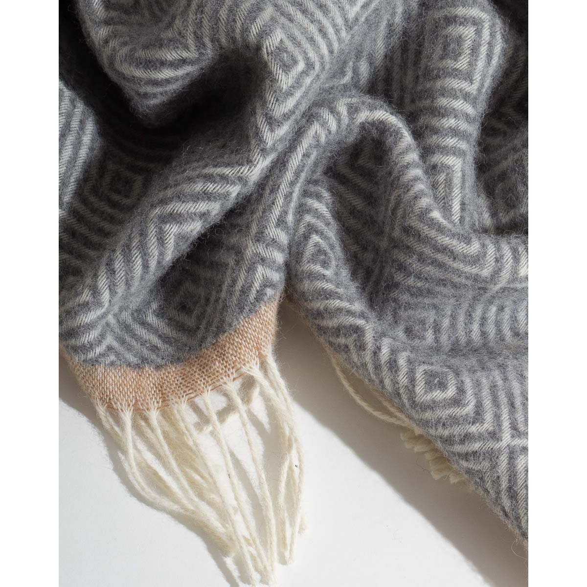 Wool Throw Blanket Venezia in grey diamond weave, draped with fringe detail