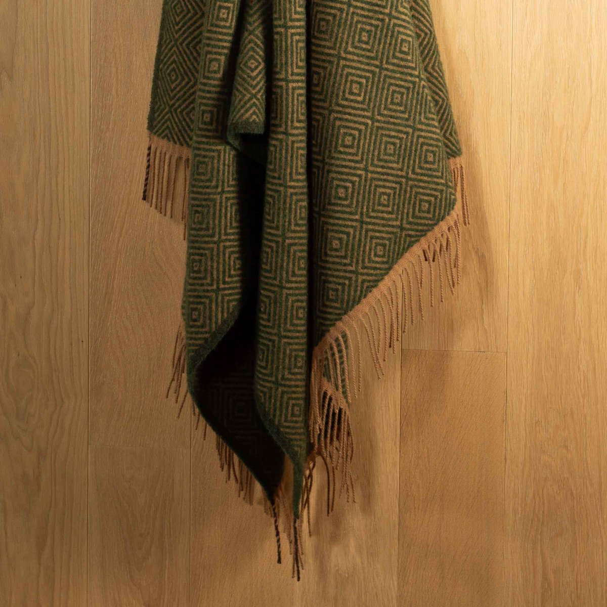 Wool Throw Blanket Venezia in leaf green diamond weave, draped with fringe detail